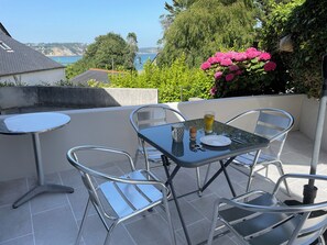 A patio with a table and chairs, a glass of beverage, and a view of the sea. - House with garden and terrace on the seafront. Quiet, at the start of the GR34. (Crozon)
