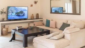 Een moderne woonkamer met een grote flatscreen televisie, een bank, een salontafel en decoratieve objecten.