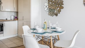 A modern kitchen with white cabinets, a dining table set with white chairs, and a decorative mirror wall.