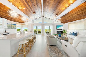 A modern kitchen with a central island, bar stools, and a dining area.