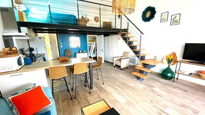Un espacio habitable moderno con cocina, comedor y una escalera que sube a un nivel superior.