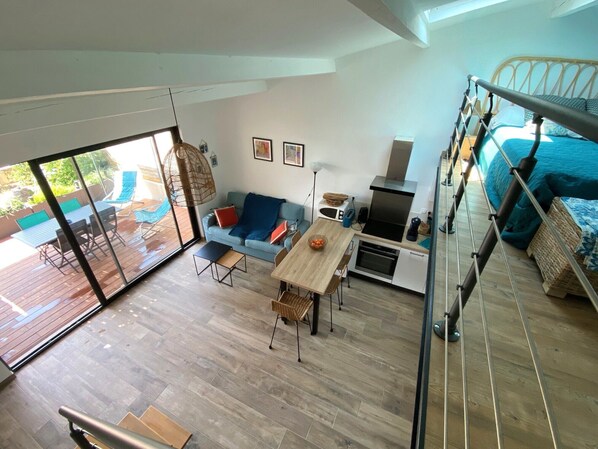 Un apartamento moderno con balcón, kitchenette, comedor y dormitorio.