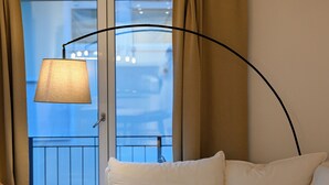 Un salón con sofá, una mesa, una lámpara y vistas al exterior.