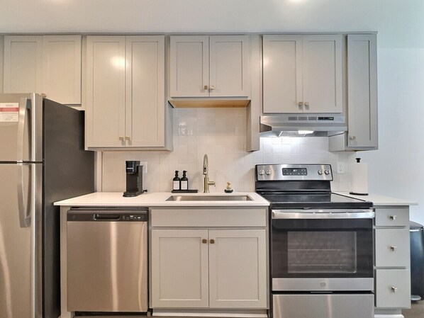 A modern kitchen with stainless steel appliances, white cabinetry, and a built-in oven. - Tranquil Getaway w/ Pool & Extra Large Balcony (Birmingham)