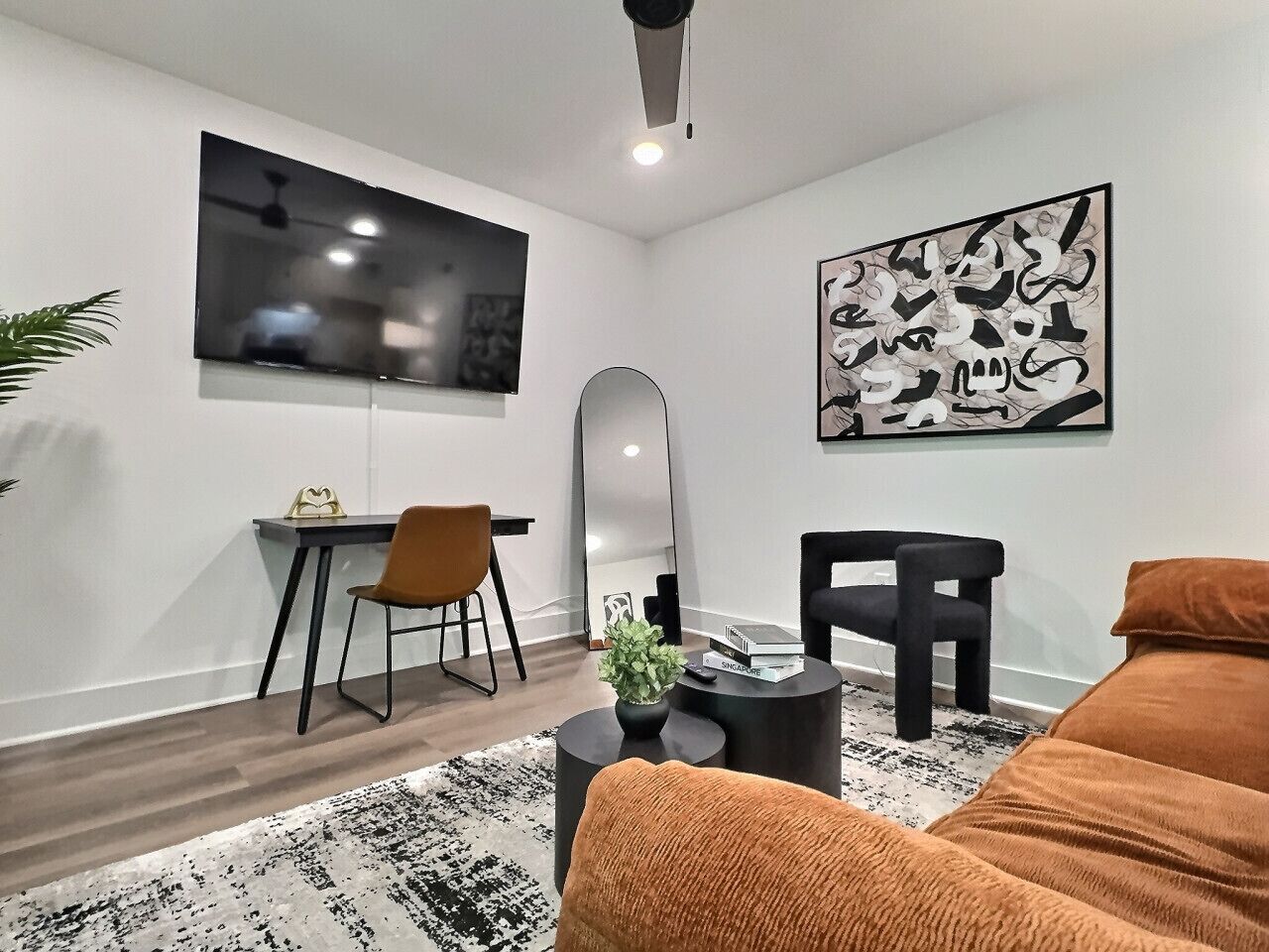 Un salon moderne comprenant un canapé, une table basse, un téléviseur, un bureau et une chaise.