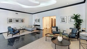 A modern lobby with a curved ceiling, black and white photographs on the walls, and a mix of seating areas including sofas and chairs.