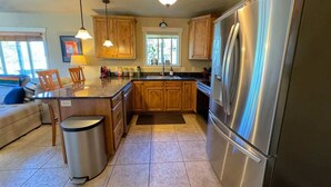 Una cocina con armarios de madera, un refrigerador de acero inoxidable y piso de baldosas.