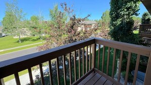 Una terraza de madera con vista a una zona residencial, con casas y árboles.