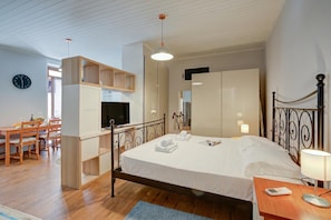 A bedroom with a bed, bedside table, lamp, TV, and a built-in wardrobe.