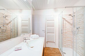 Ein modernes Badezimmer mit einer gläsernen Duschkabine, einem weißen Waschbecken und einem Handtuch auf der Ablagefläche.