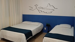 A room with two single beds, a ceiling fan, and a wall decoration.