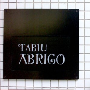 A black sign with white lettering spelling 'TABIU ABRIGO' on a tiled wall. - Arima Onsen Abrigo (Kobe)