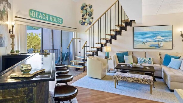 A modern living room with a staircase, a bar area, and a couch.