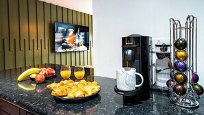 A modern kitchen with a coffee machine, a fruit bowl, croissants, and a television on the wall. - The Arran Suite - Your Stylish Scottish Getaway! (Glasgow)