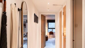 A hallway with a carpeted floor, a mirror on the left, and a door on the right. - The Arran Suite - Your Stylish Scottish Getaway! (Glasgow)