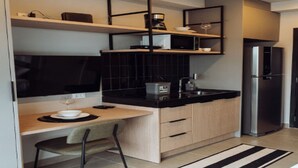 A modern kitchen with a black countertop, wooden cabinets, a built-in microwave, and a stainless steel refrigerator. - OSCAR FREIRE 1820 (Pinheiros São Paulo)