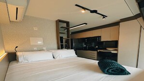 A modern hotel room with a large bed, a neatly made bed, a kitchen area, and a small seating area. - OSCAR FREIRE 1820 (Pinheiros São Paulo)