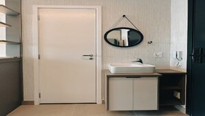 A modern bathroom with a white door, a round mirror, a sink, and a cabinet. - OSCAR FREIRE 1820 (Pinheiros São Paulo)