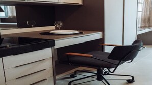 A modern kitchen with a dining area, featuring a black office chair, a white plate, and two wine glasses on the counter. - OSCAR FREIRE 1820 (Pinheiros São Paulo)