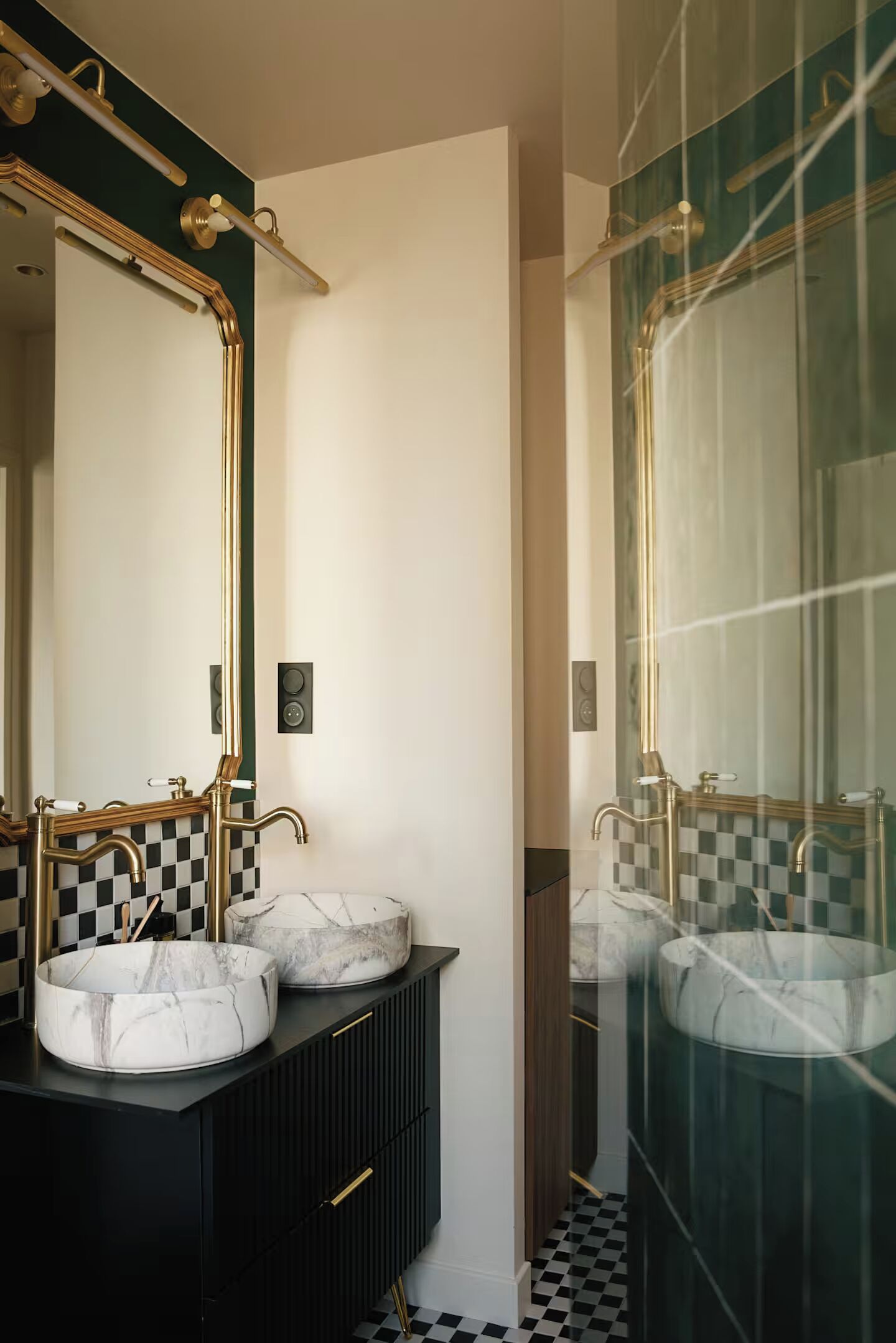 Een moderne badkamer met twee marmeren wasbakken, zwarte kastjes en gouden details.