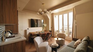 A modern living room with a dining area, a sofa set, and a view of the city through large windows. - Résidence Louvre  (Paris)