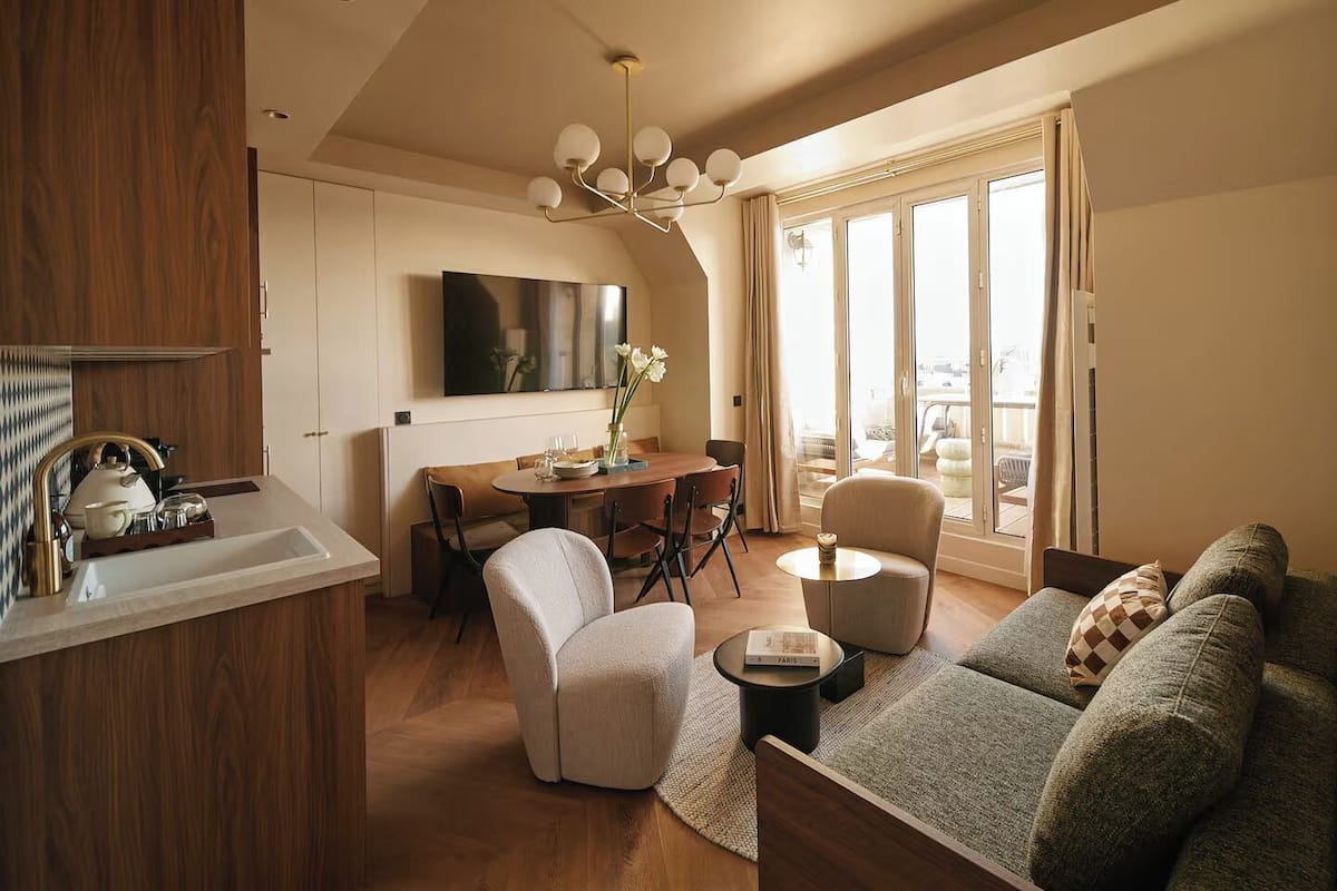 A modern living room with a dining area, a sofa set, and a view of the city through large windows.