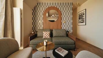 A modern living room with a sofa, two side tables, a coffee table, and a checkered throw pillow.