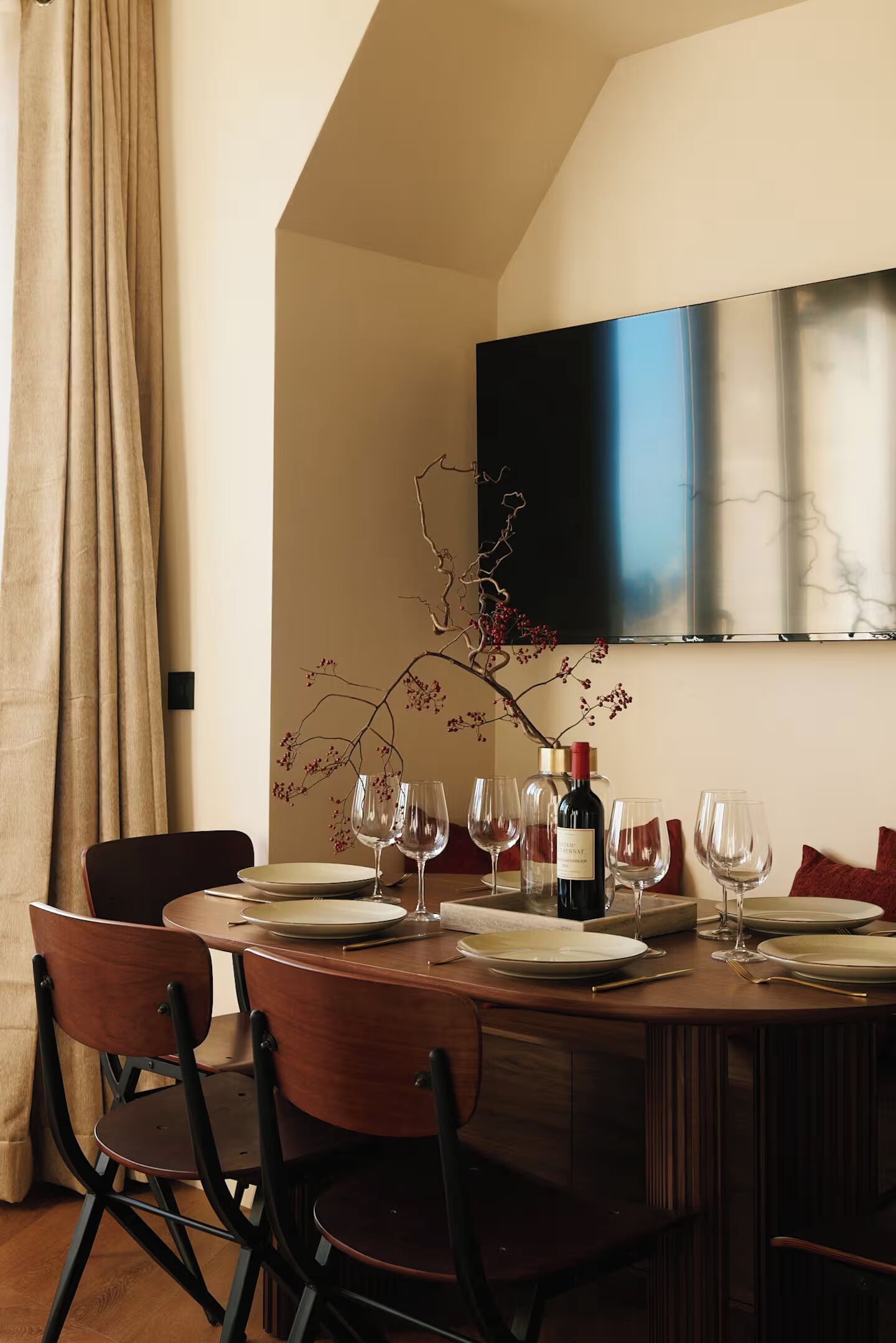 A dining area with a round table set for six, a wine bottle, and empty wine glasses.