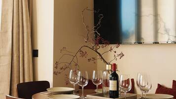 A dining area with a round table set for six, a wine bottle, and empty wine glasses.