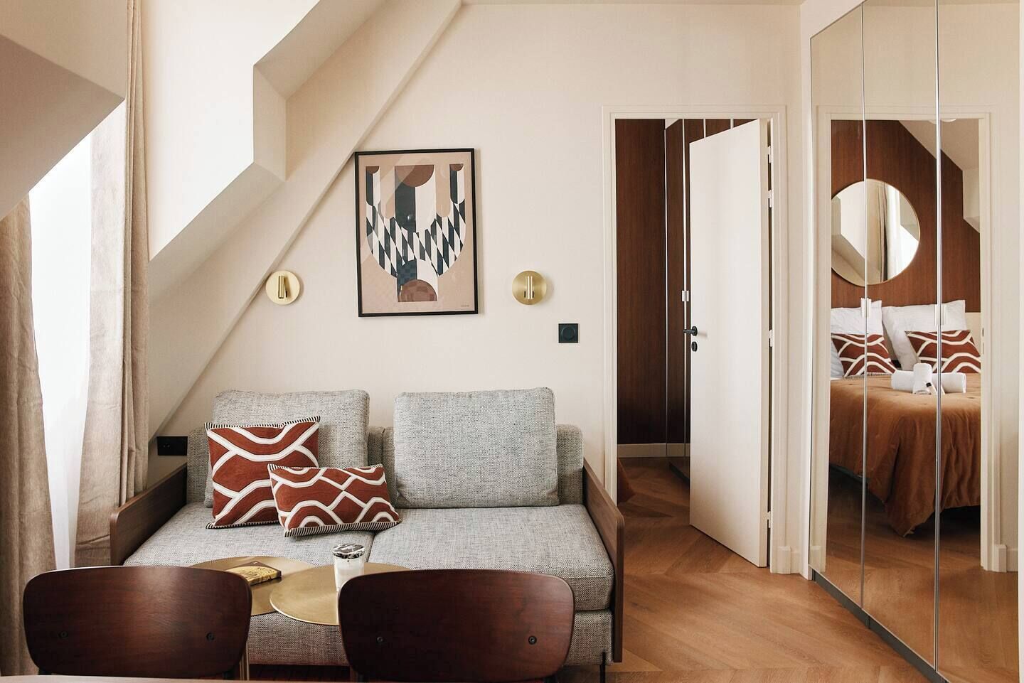 Una habitación de hotel moderna con sofá, una mesa de comedor y un espejo.
