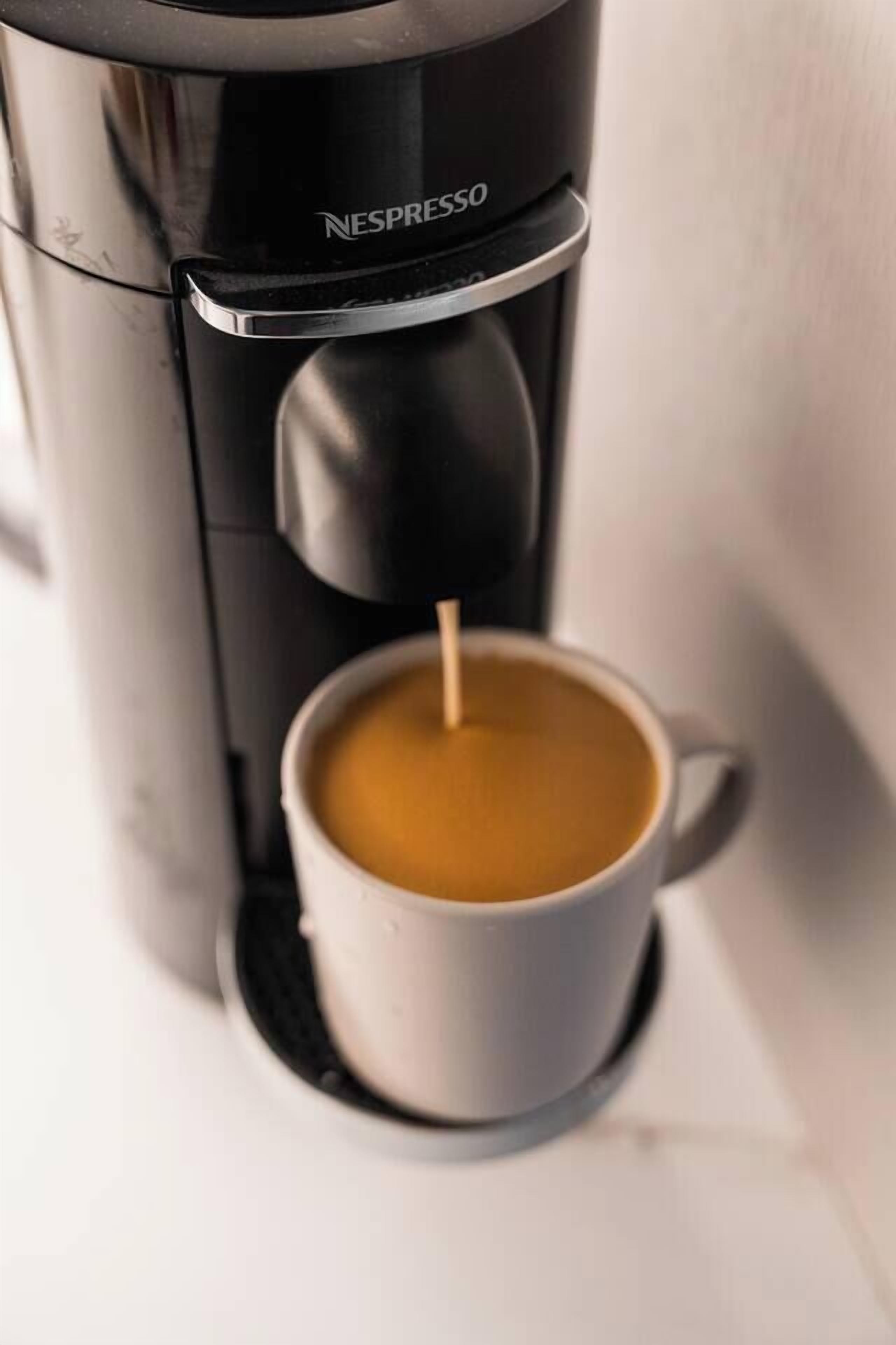 A Nespresso coffee machine dispensing coffee into a white cup.