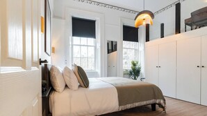 A bedroom with a bed, bedside tables, a lamp, and a wardrobe.
