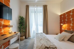 A modern hotel room with a bed, a TV, a desk, and a potted plant. - Cornelia Vatican Suites (Rome)