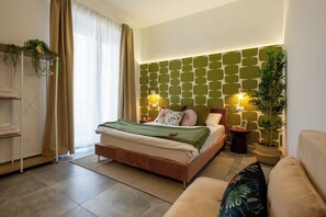 A modern bedroom with a bed, bedside tables, a sofa, and a potted plant. - Cornelia Vatican Suites (Rome)