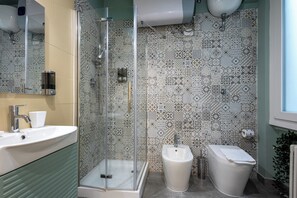 A bathroom with a glass-enclosed shower, a sink, and a toilet. - Cornelia Vatican Suites (Rome)