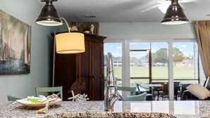 Una cocina con encimera de granito, pileta de acero inoxidable e iluminación colgante.