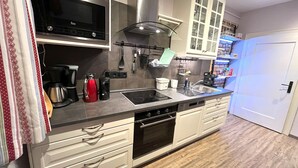 Een moderne keuken met roestvrijstalen apparatuur, witte kasten en een houten vloer.