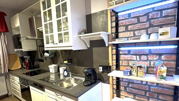 Een moderne keuken met witte kastjes, een ingebouwde oven en een koffieapparaat.