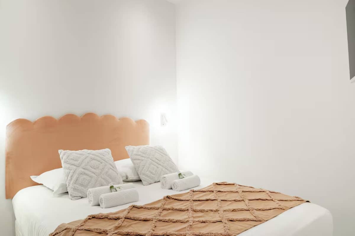 Un lit bien fait, avec une tête de lit marron, du linge de lit blanc et deux coussins décoratifs.