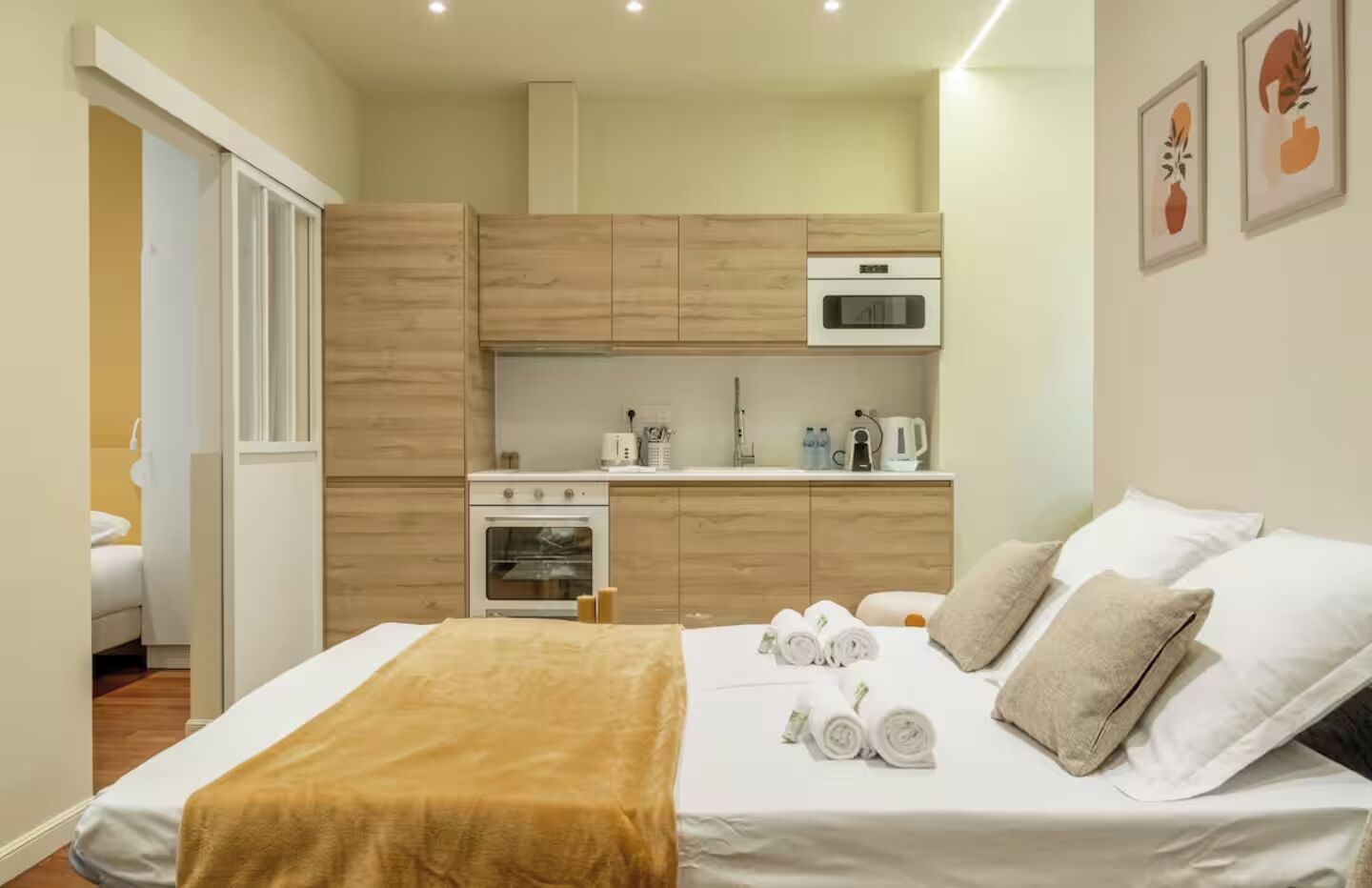 A compact hotel room with a bed, a small kitchenette, and a bathroom visible through an open door.