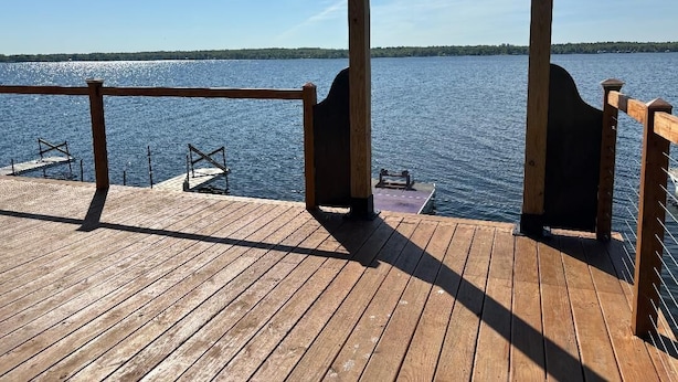 Une terrasse en bois dotée d’une rambarde, qui offre une vue sur une étendue d’eau.