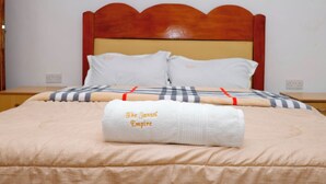 Una cama bien hecha con un edredón a rayas y una toalla con la etiqueta 'The Janssol Empire'.