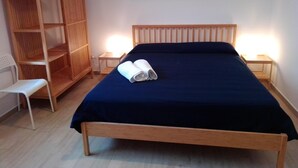 Ein Schlafzimmer mit einem hölzernen Bett, einem Kleiderschrank, einem kleinen Tisch und einer Bank.