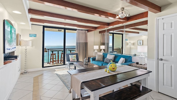 A spacious living area with a balcony, a dining table, and a sofa.