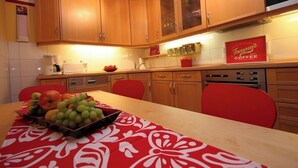 A kitchen with wooden cabinets, a coffee machine, and a table with a fruit bowl. - Hof Eckhorst, Apartment Sonnenschein (Güby)