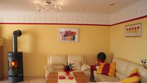 A cozy living room with a fireplace, a sofa, a coffee table, and a potted plant. - Hof Eckhorst, Apartment Sonnenschein (Güby)