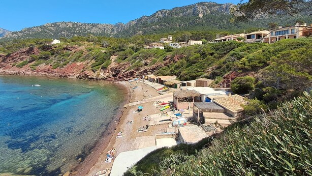 Eine Küstenlandschaft mit Strand, Gebäuden und Bergen.