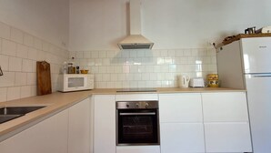Eine Küche mit weißen Schränken, einem eingebauten Backofen, einer Mikrowelle, einer Spüle und einem Kühlschrank.
