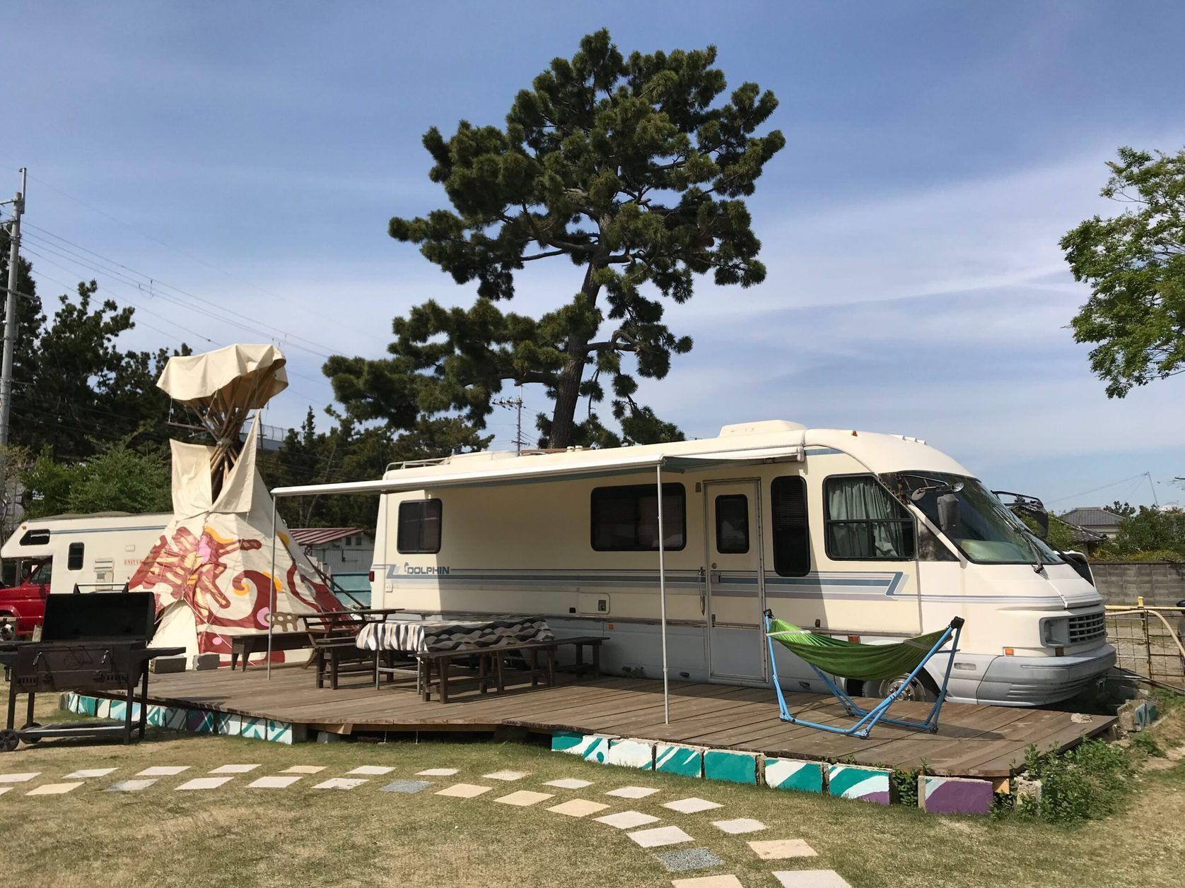 A recreational vehicle with a covered deck area, a grill, and a hammock.