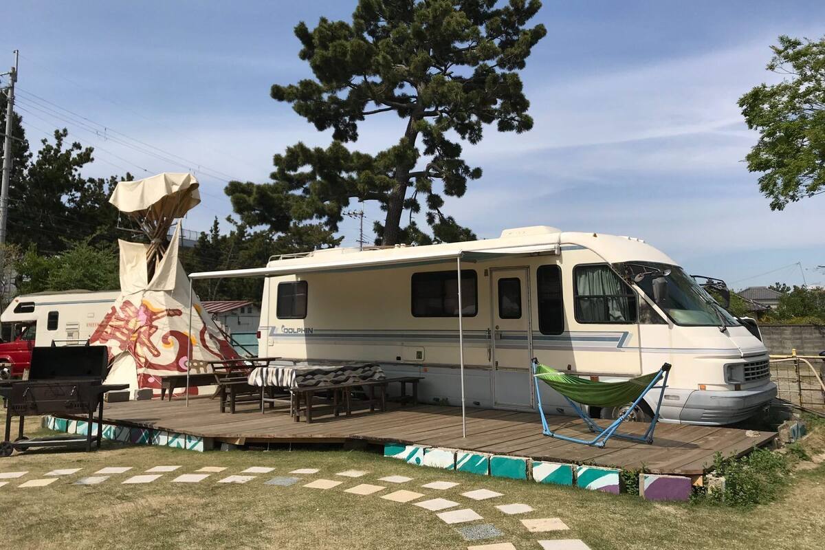 A recreational vehicle with a covered deck area, a grill, and a hammock.